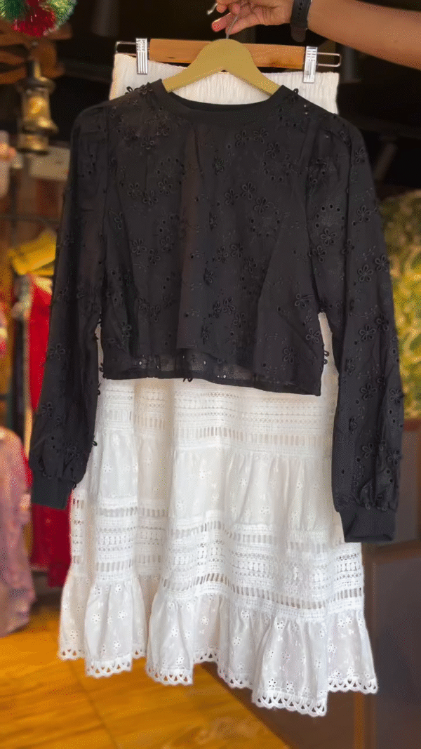 Black Floral Embroidered Sheer Long Sleeve Crop Top Paired with White High-Waisted Tiered Cotton Skirt Featuring Intricate Lace Cutwork and Eyelet Detailing – Perfect for Chic Daywear or Casual Outings